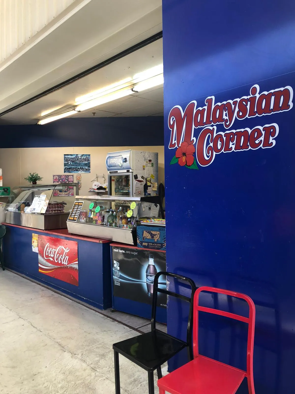 The Malaysian Corner counter, painted deep blue, with food display cabinets and a drinks fridge behind it.