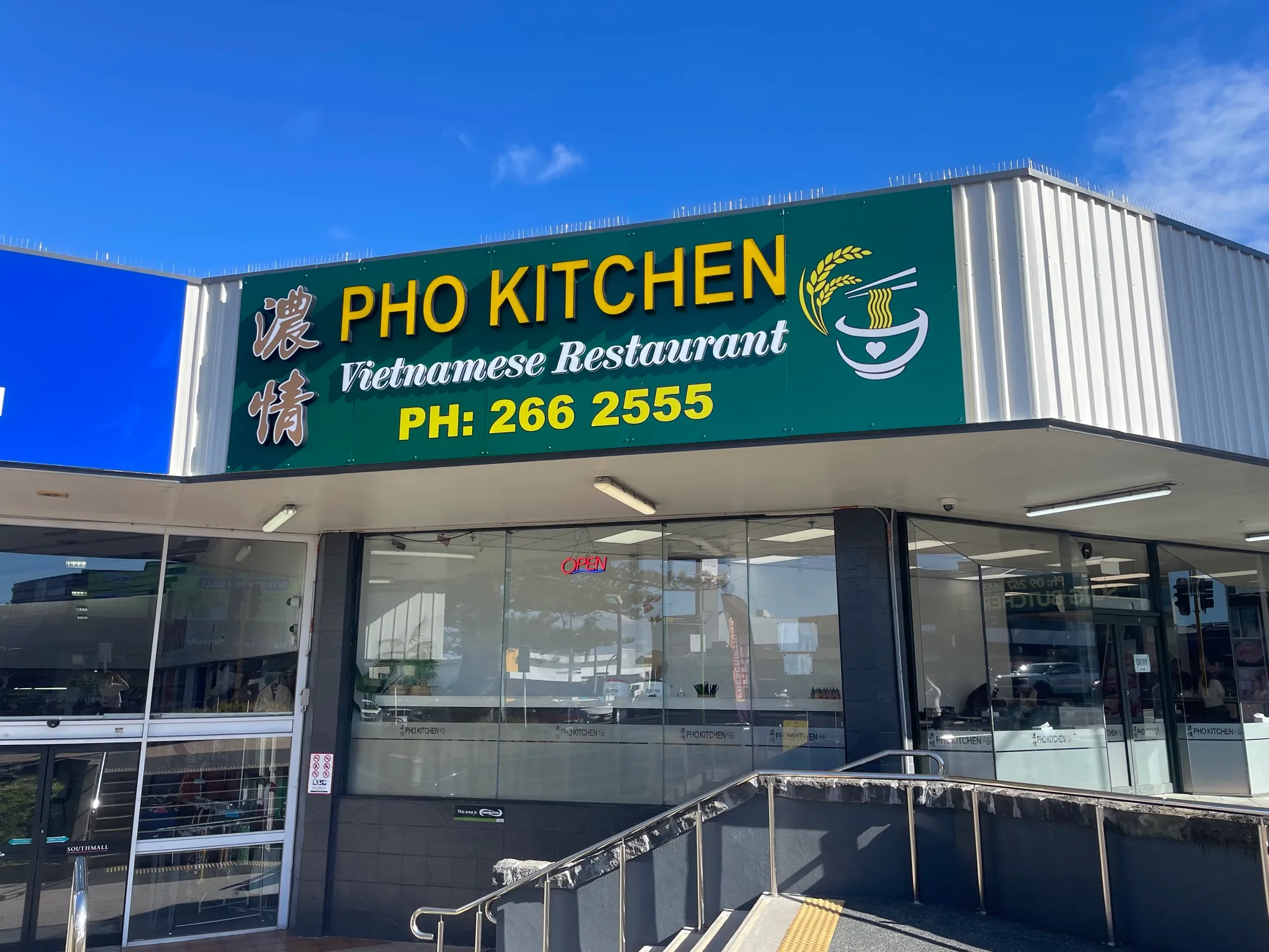 The Pho Kitchen shopfront under a green sign reading "Vietnamese Restaurant", with a noodle bowl illustration alongside the lettering.
