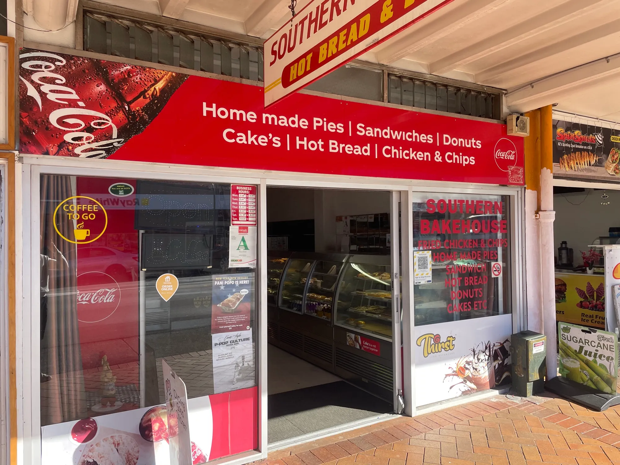 The Southern Bakehouse shopfront, its red sign listing home made pies, sandwiches, donuts and hot bread, with bakery cabinets inside the open doorway.