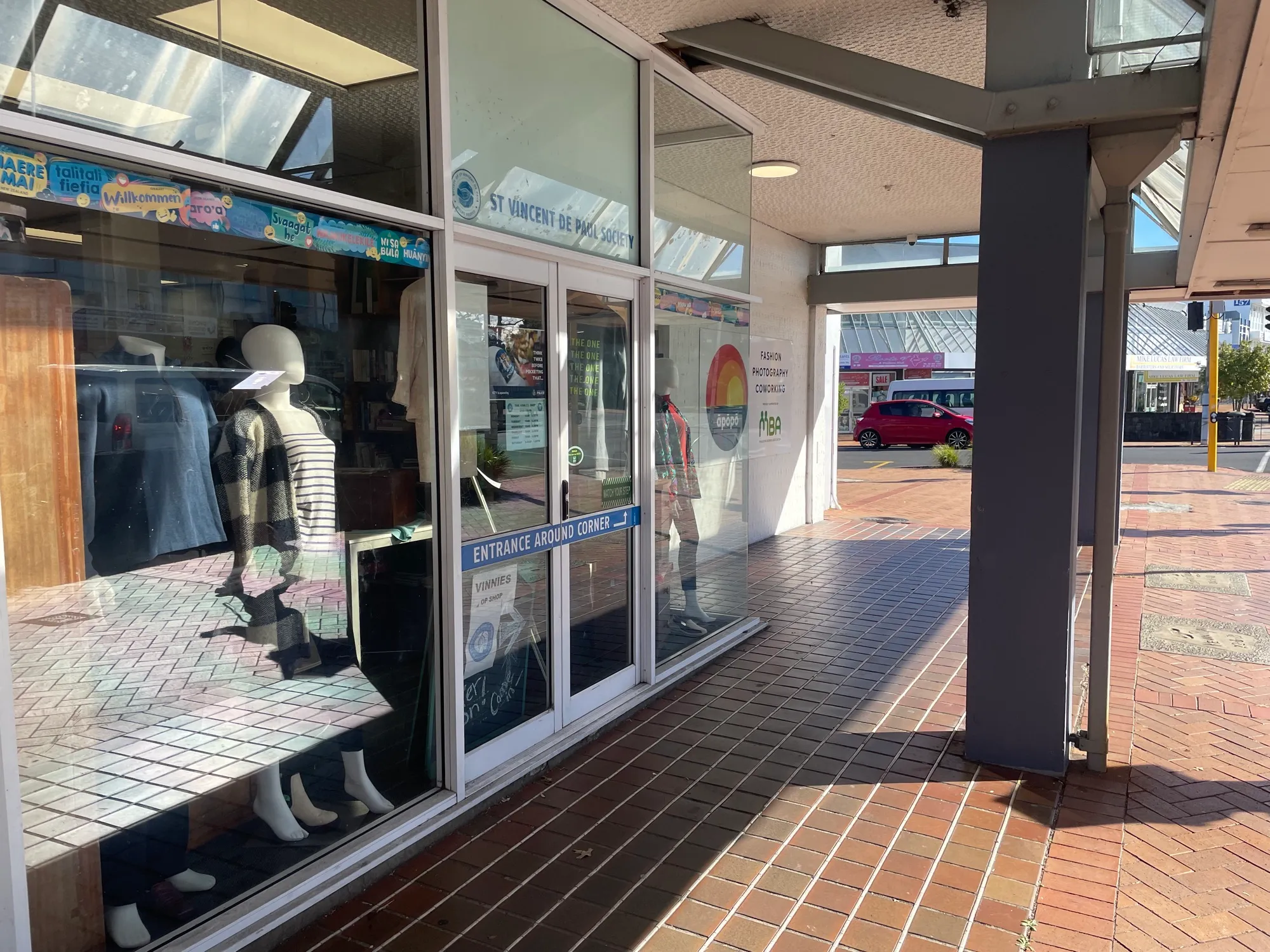 Southmall's covered walkway, its brick paving opening out to the street where cars and a van are parked, with the St Vincent de Paul op shop window alongside.